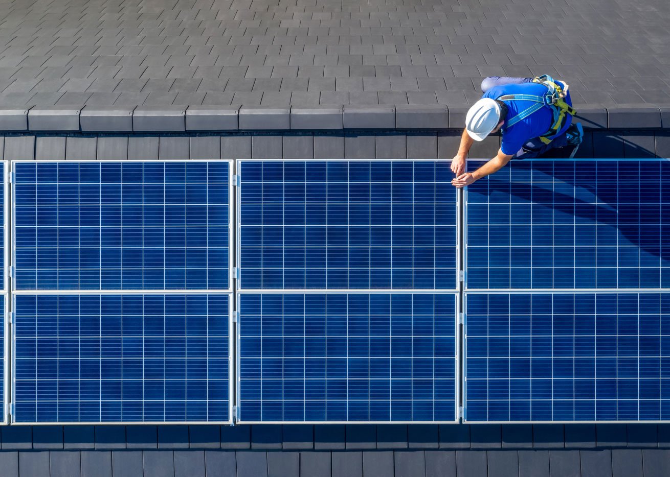 worker installing solar panels on roof